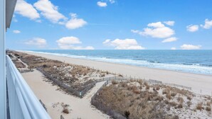 A beach view with a wooden fence, sandy beach, and ocean.