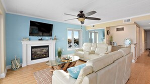 A living room with a fireplace, a television, a sofa, and a ceiling fan.