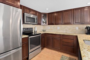 A kitchen with wooden cabinets, stainless steel appliances, and a granite countertop.
