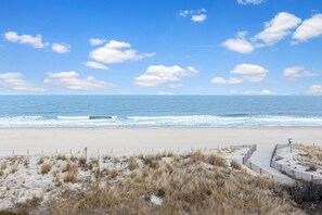 A beach with a wooden fence and a signpost.