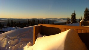 Schneebedeckte Landschaft mit einer Holzterrasse mit Blick auf ein Bergmassiv.