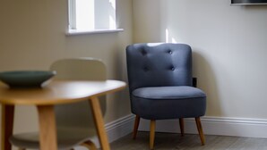 Een kamer met een blauwe stoel, een houten tafel en een kom.