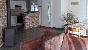 A modern kitchen with a stone island, a dining area with a table and chairs, and a cozy living space with a sofa. - Charming cottage near the sea (Saint-Germain-sur-Ay)