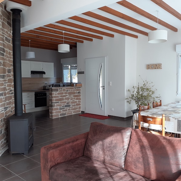 A modern kitchen with a stone island, a dining area with a table and chairs, and a cozy living space with a sofa.