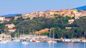 A coastal town with historic buildings, a marina with boats, and a prominent church tower. - Air-conditioned 75m2 duplex with spa and panoramic views! (Porto-Vecchio)