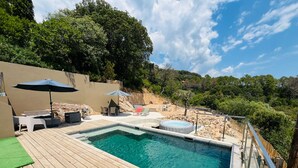 A swimming pool with a wooden deck, lounge chairs, and umbrellas. - Air-conditioned 75m2 duplex with spa and panoramic views! (Porto-Vecchio)