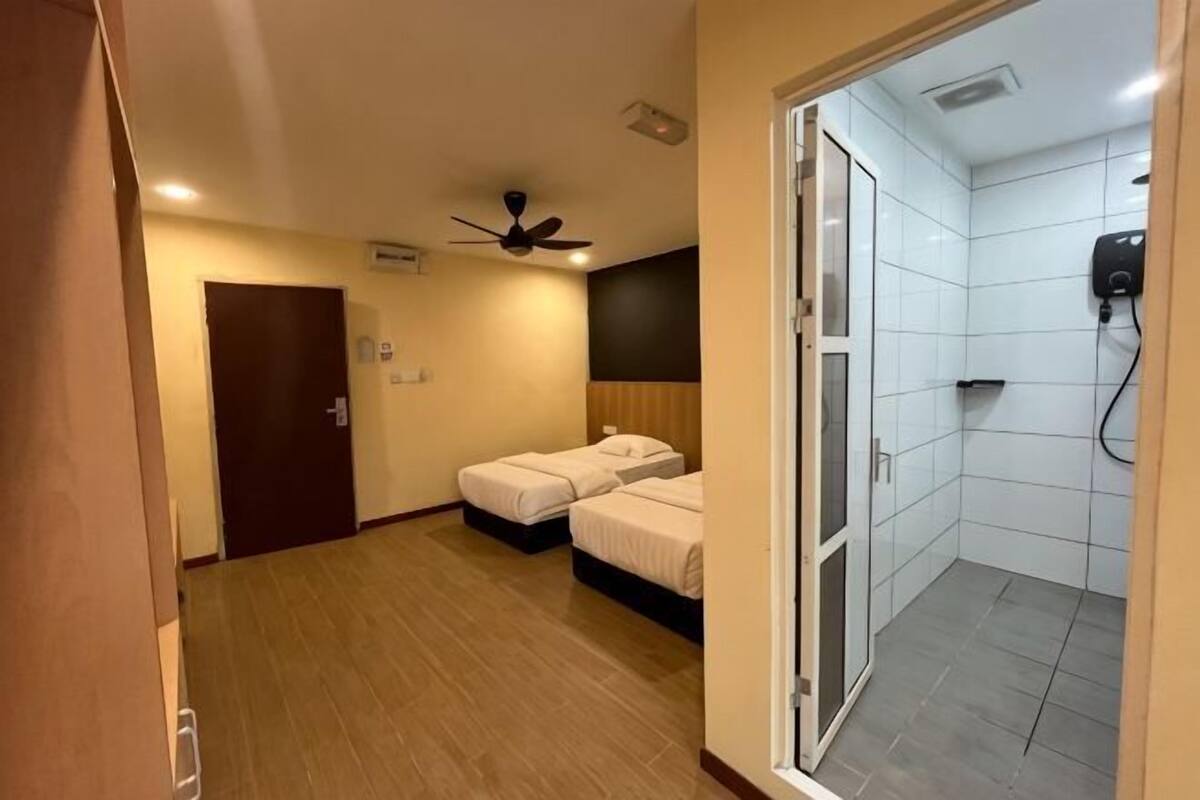 A hotel room with a bed, a shower, a ceiling fan, and a door.