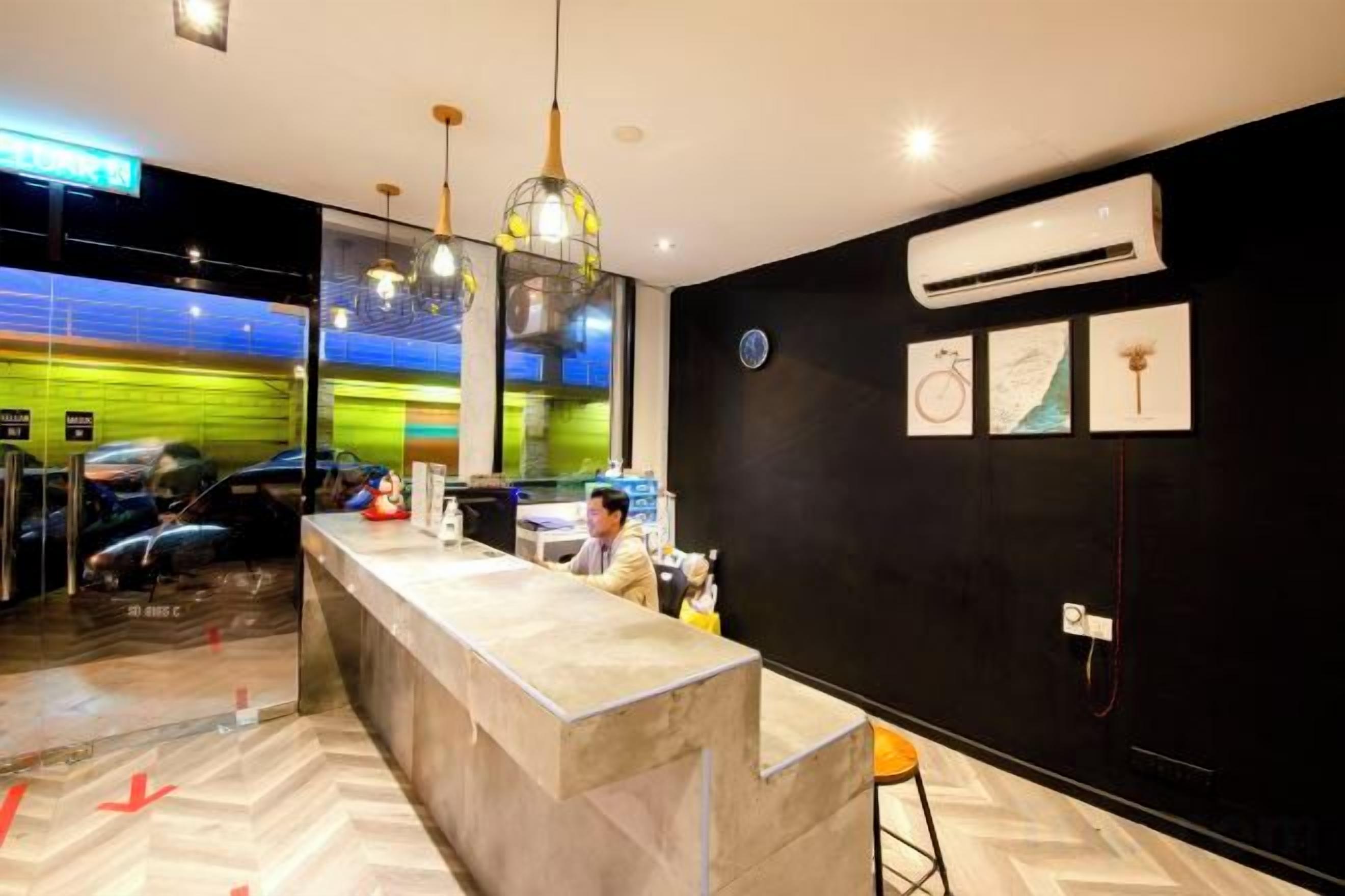 A hotel reception area with a marble counter, a black wall with framed artwork, and a large air conditioning unit.