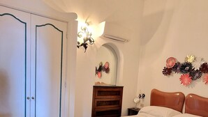 Une chambre à coucher comprenant un lit, une chaise, une commode et un luminaire fixé au mur.