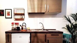 A compact kitchen with wooden cabinets, a built-in sink, and a small refrigerator.