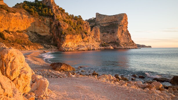 Un paisaje costero con acantilados rocosos y una playa de guijarros.