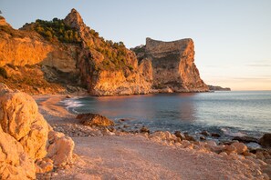 A coastal landscape with rocky cliffs and a pebble beach. - Casa Inca, year-round villa over Moraira with heatable pool and great views (Benitachell Alicante)