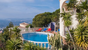 Una piscina con vista al paisaje, rodeada de cactus y palmeras.