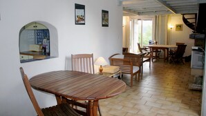 Un coin repas avec une table et des chaises en bois, une lampe et une vue sur la cuisine.