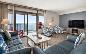 Une chambre d’hôtel moderne dotée d’un balcon, d’un téléviseur à écran plat et d’un ensemble de canapés.