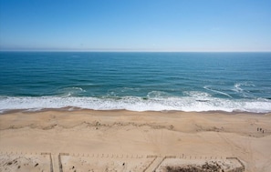 A beach with a clear view of the ocean, sandy shore, and footprints leading to the water. - Stunning 3BR 2BA Oceanfront Unit, Featured on HGTV's Beachfront Bargain Hunt! (Ocean City)