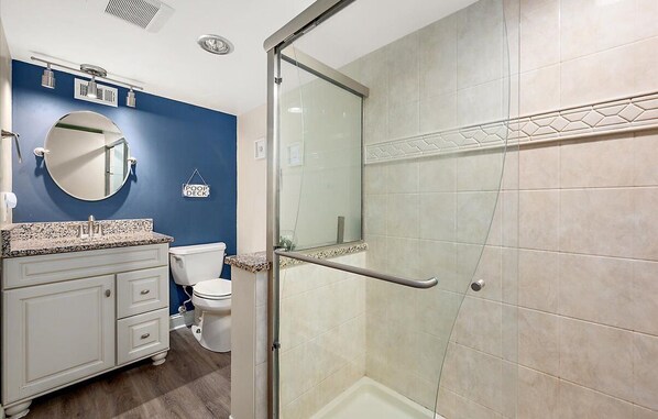 Une salle de bain avec douche, toilettes et lavabo.