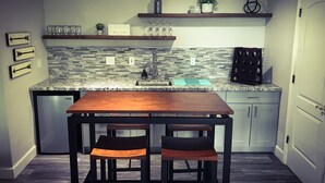 A compact kitchen with a wooden table and two chairs, a built-in sink, and a backsplash with a mosaic tile design.