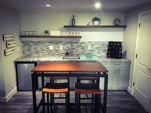 Una cocina funcional con una mesa de madera y dos sillas, un lavamanos empotrado y un salpicadero con diseño de mosaico.