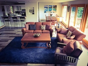 Relax in this inviting living space with a large window offering a view of the outdoors, a dining area, and a kitchen.