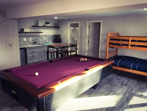 Un espacio habitable compacto con mesa de billar, kitchenette y litera.