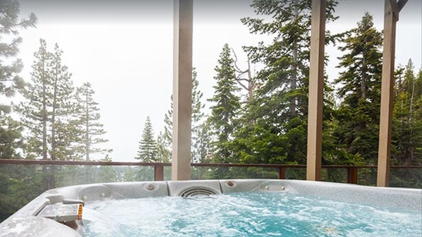 A hot tub with a view of tall trees.