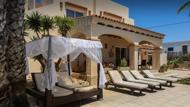 A pool area with lounge chairs and a covered seating area.