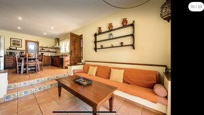 A living room with a sofa, coffee table, and a kitchen in the background.