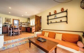 Una sala de estar con sofá, una mesita de centro y una cocina al fondo.