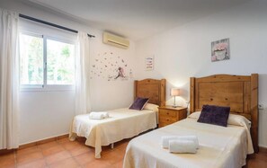 Un dormitorio con dos camas, una ventana con cortinas, aire acondicionado y un adorno en la pared.