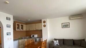 A compact living space with a dining area, kitchenette, and a sofa.
