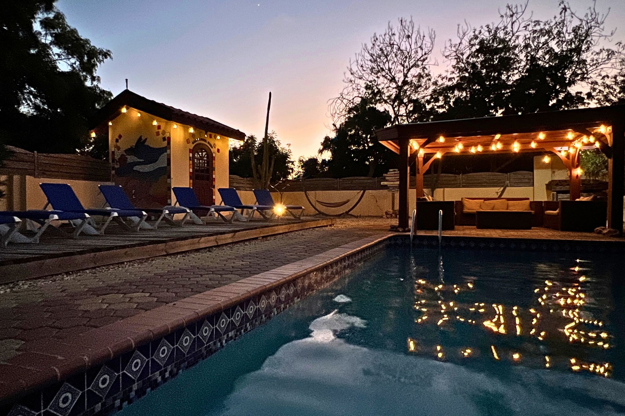 A swimming pool with lounge chairs and a covered seating area.
