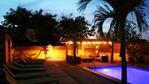 Ein Poolbereich mit Liegestühlen, eine überdachte Sitzecke mit Lichterketten und ein Schwimmbecken.