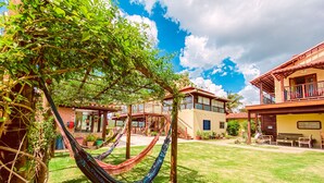 A two-story house with a balcony, a hammock, and a well-maintained lawn. - Pousada Quintal da Lua (Capitólio)