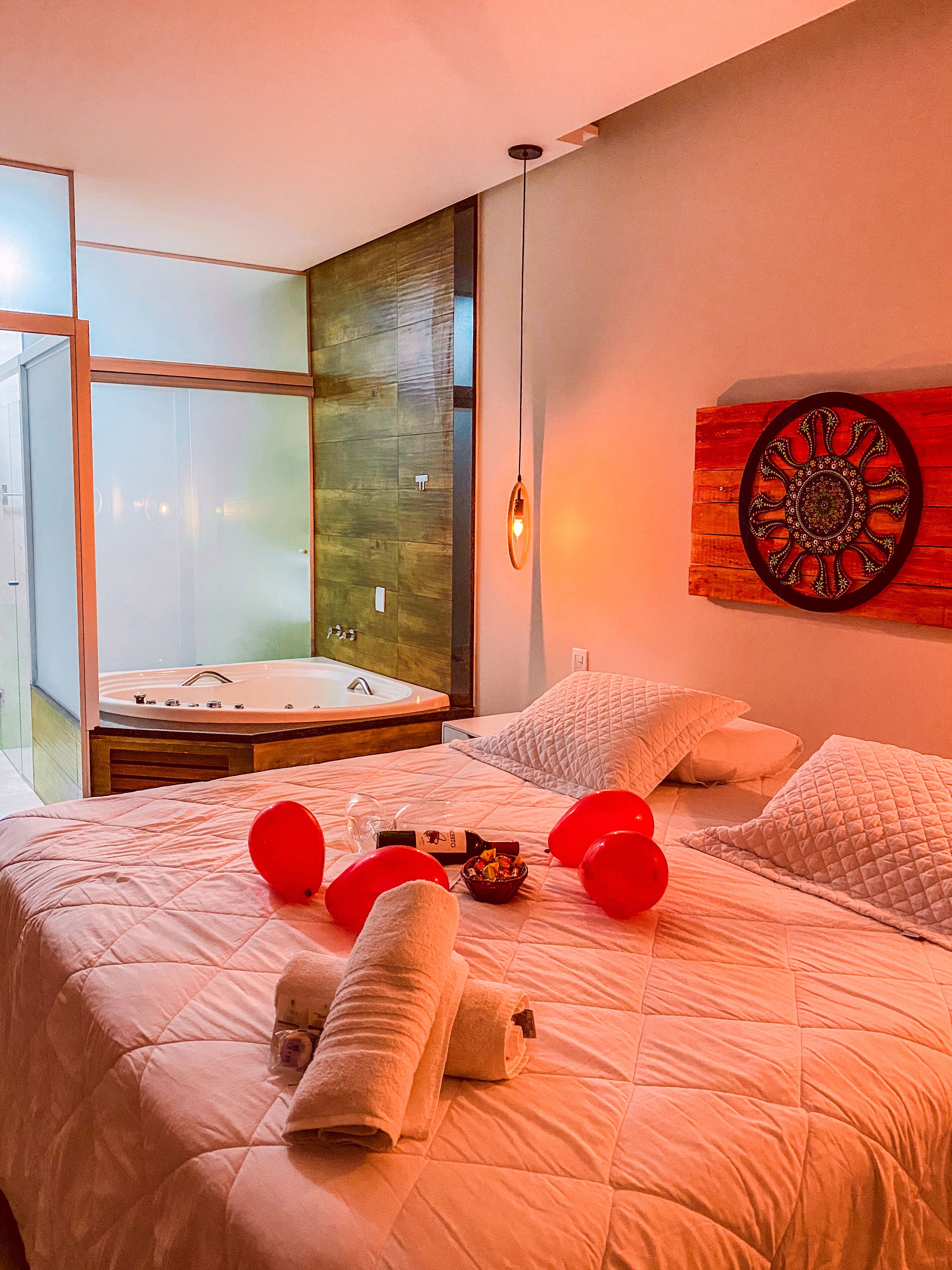 A modern hotel room with a large bed, a view of a spa area, and a decorative wall piece.
