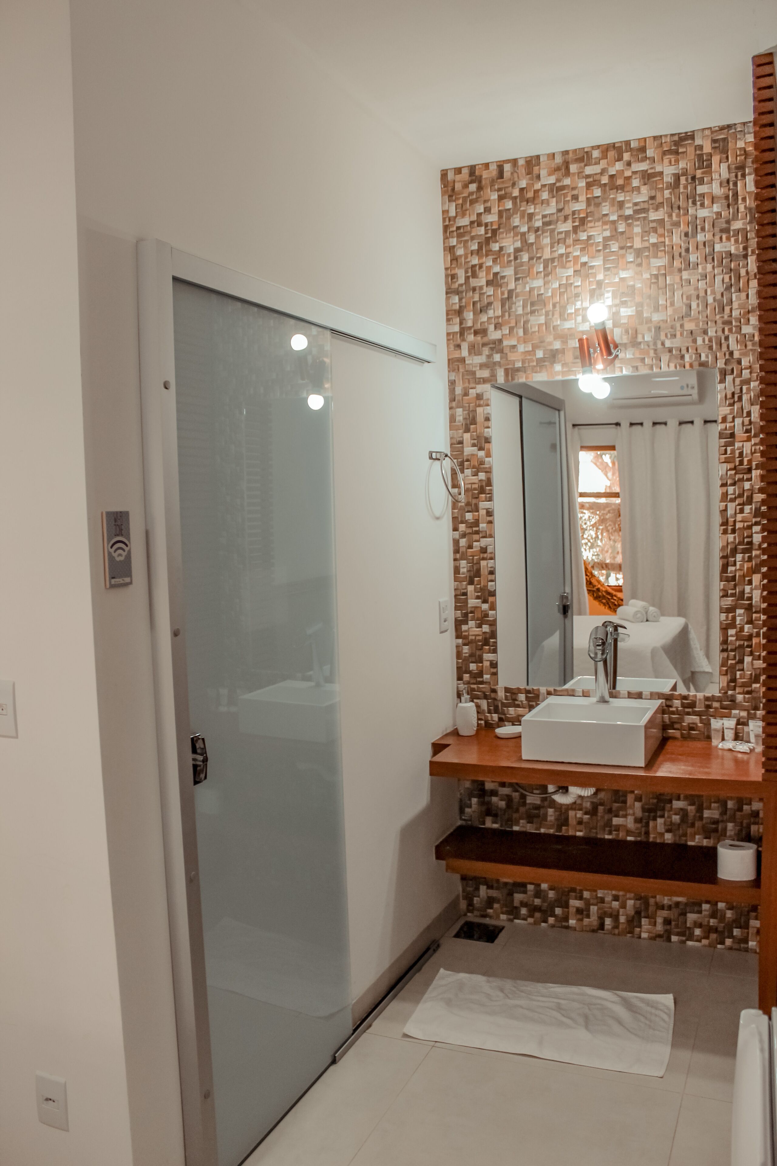 A modern bathroom with a glass door, a white sink, and a mirror.