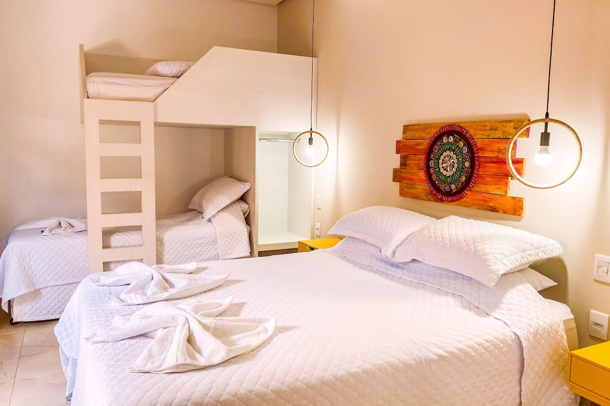 A room with bunk beds, a wooden wall decoration, and a yellow bedside table.