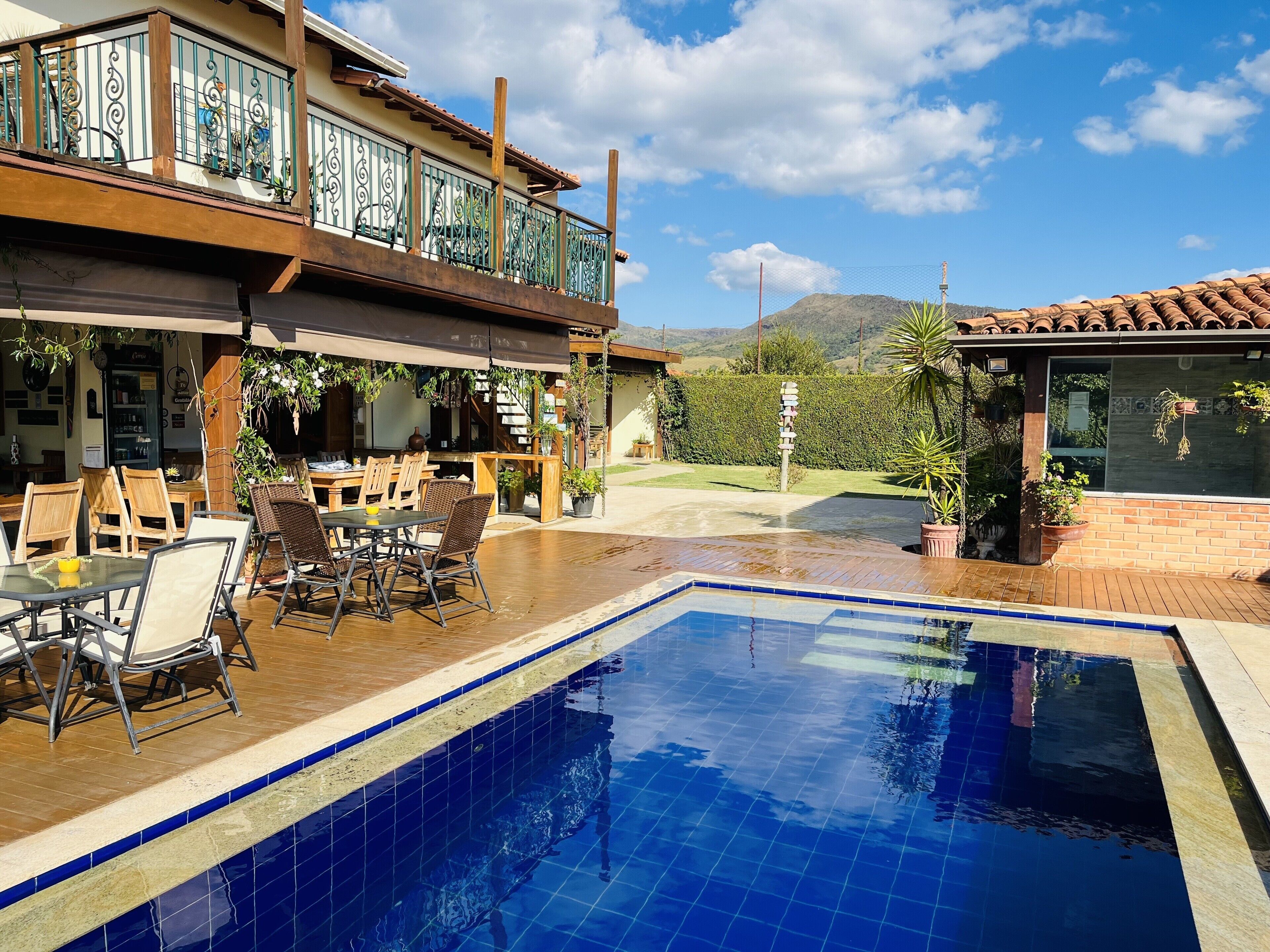 A pool area with a wooden deck, outdoor seating, and a view of the mountains.