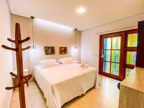 A bedroom with a bed, a wooden coat rack, two wall-mounted light fixtures, and a door with stained glass windows.