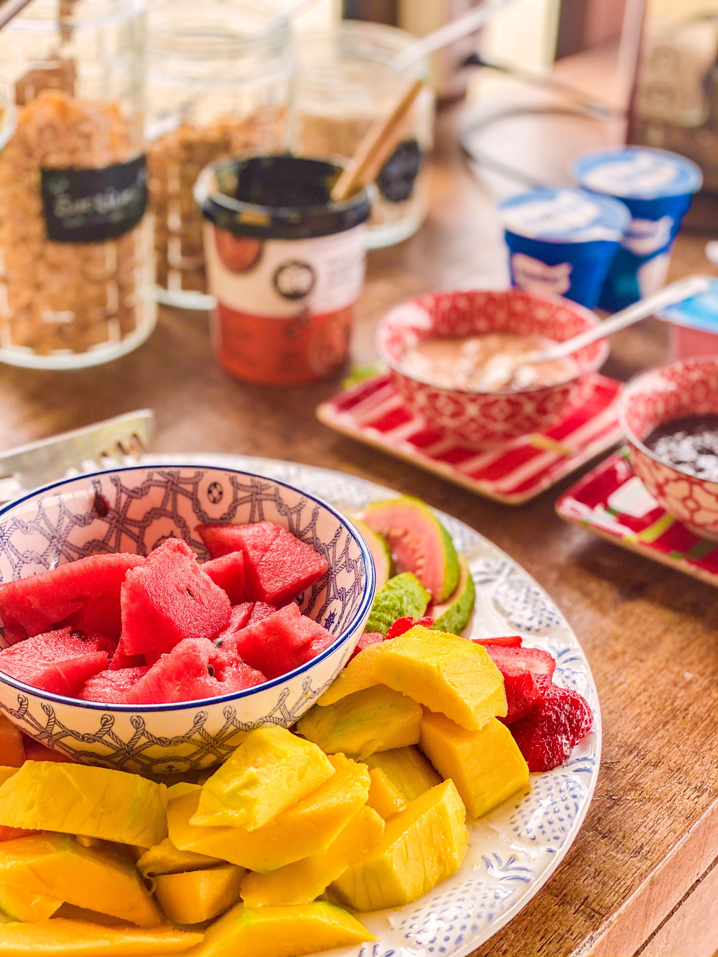 A table with a bowl of fruit salad, including watermelon, mango, and strawberries.