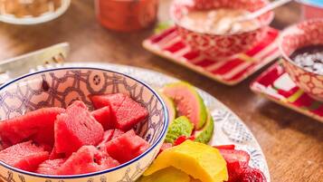 A table with a bowl of fruit salad, including watermelon, mango, and strawberries.