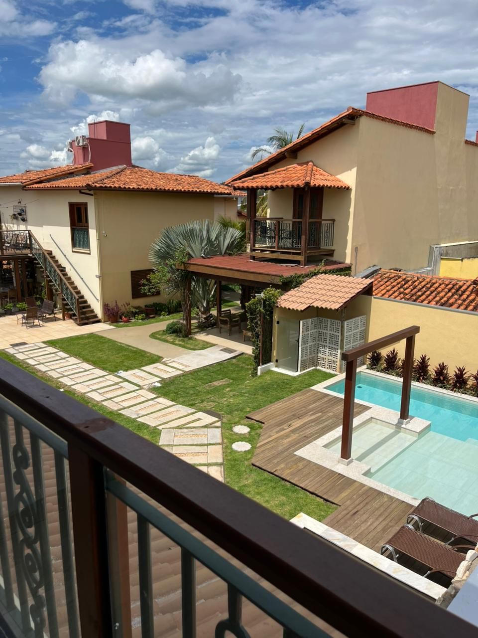 A residential area with a swimming pool, a covered patio, and a staircase leading to a balcony.