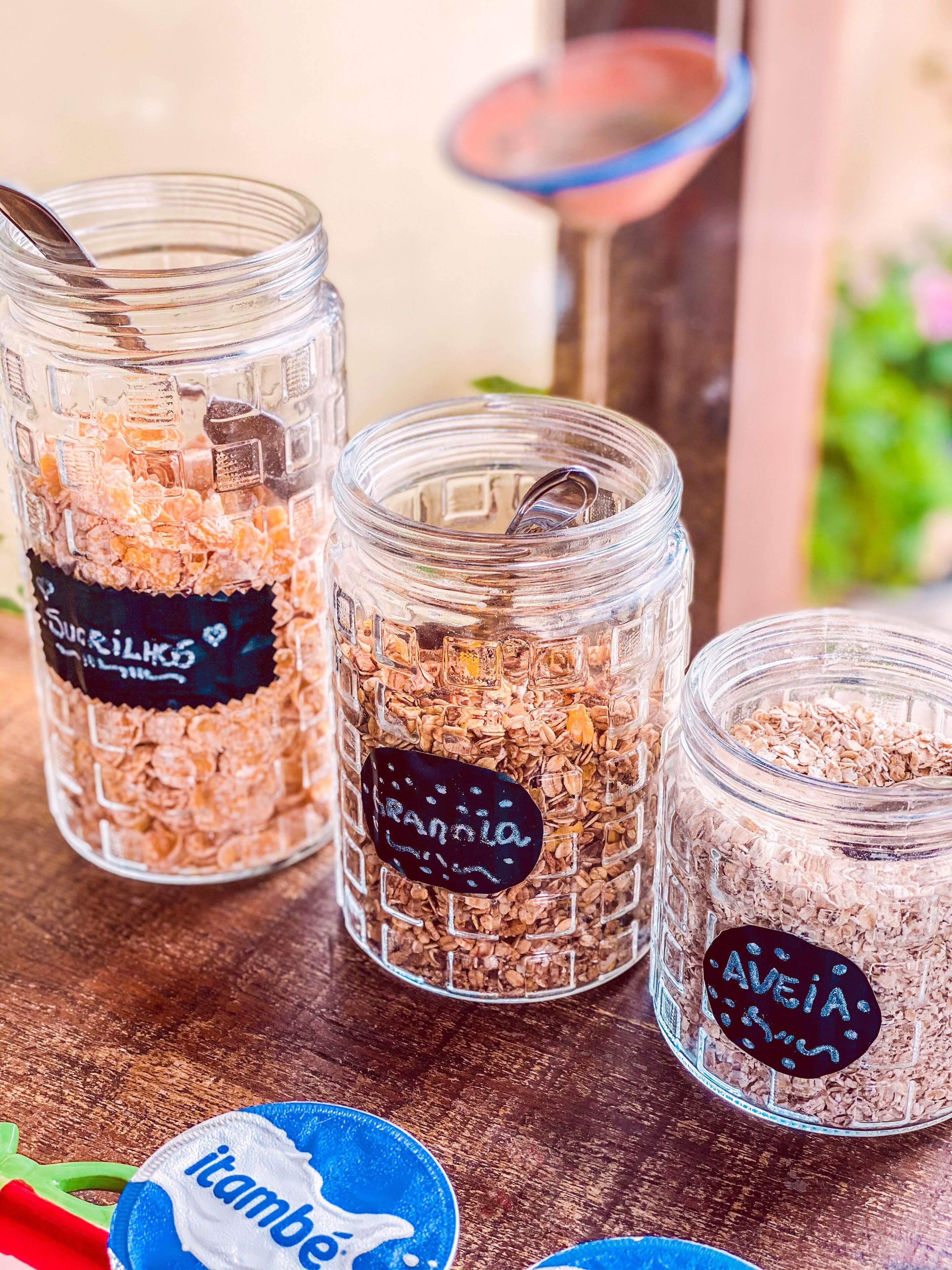 Três potes de vidro cheios de granola sobre uma superfície de madeira.