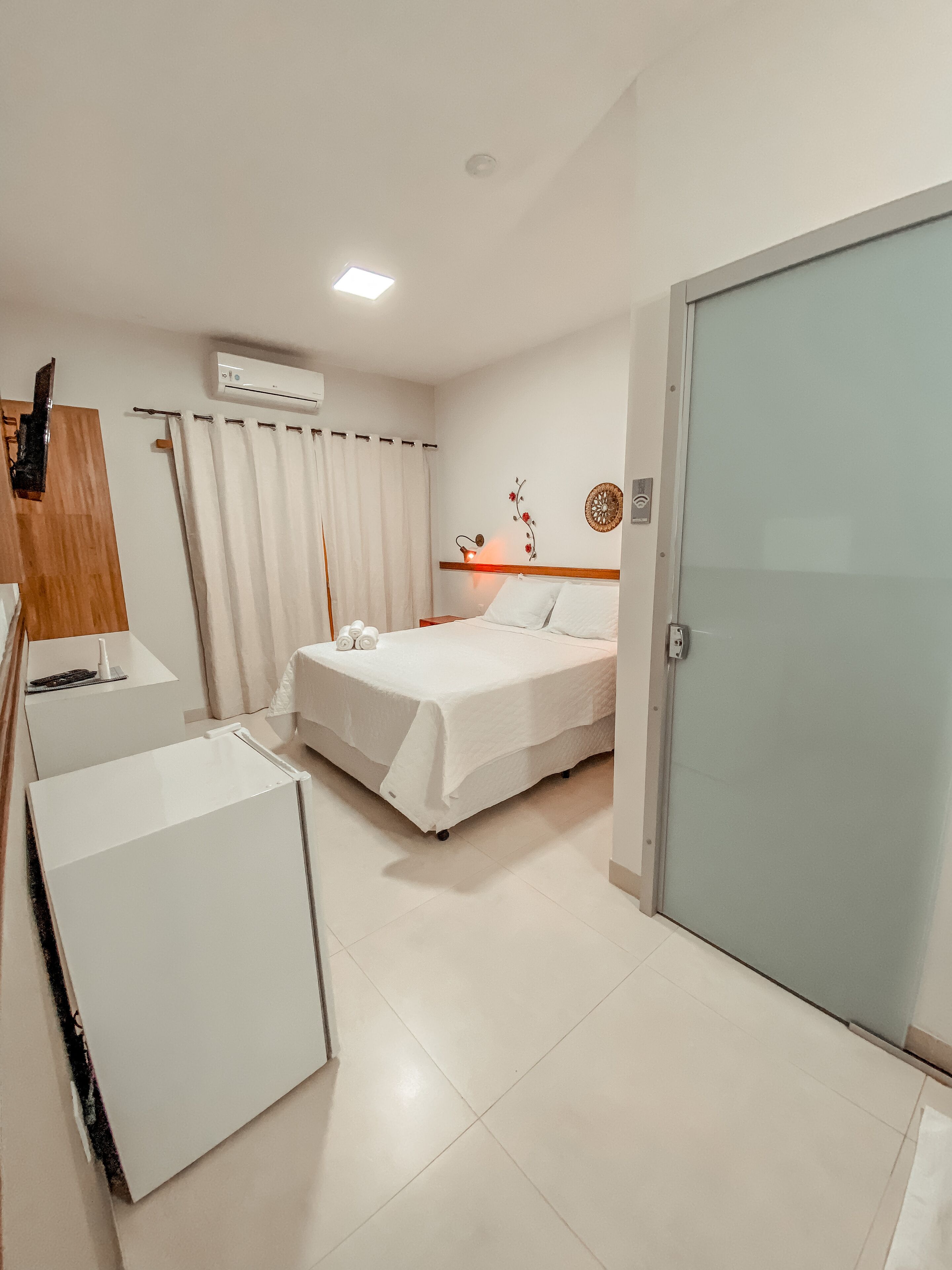 Una camera d'albergo con un letto, una scrivania, una sedia, un armadio e un condizionatore.