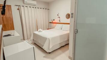 Una camera d'albergo con un letto, una scrivania, una sedia, un armadio e un condizionatore.
