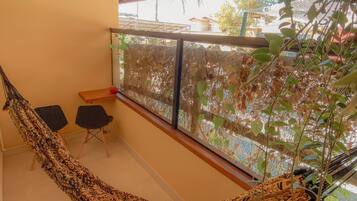 Una hamaca en una habitación con vistas a una casa y árboles. Hay dos sillas y una mesa.