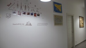 A hallway with a wall decorated with travel-themed drawings and photographs, a map, and a framed picture. - Dimora Fraula Guest House (Agrigento)