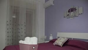 A bedroom with a bed, a bedside table, a lamp, and a wall-mounted air conditioner. - Dimora Fraula Guest House (Agrigento)