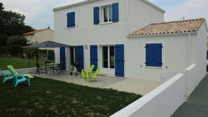 A two-story house with a patio area featuring outdoor furniture and a grill.
