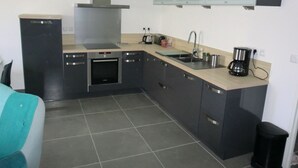 A compact kitchen with a stove, oven, sink, and a coffee maker.